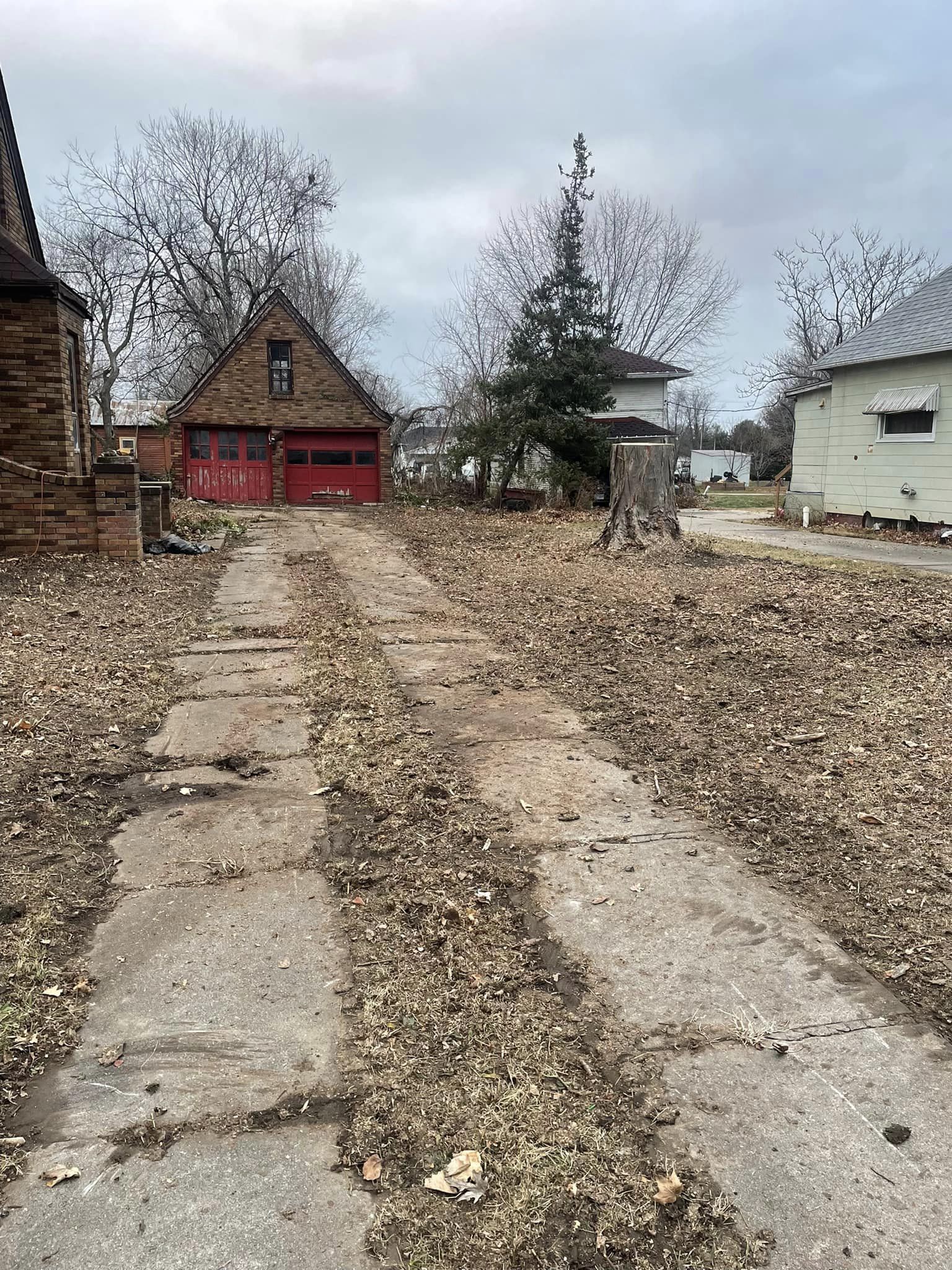 A dirt road leading to a house with a red garage door.