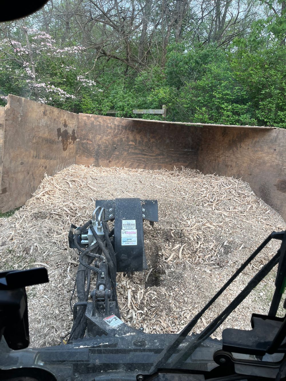 A large pile of wood chips is being loaded into a truck.