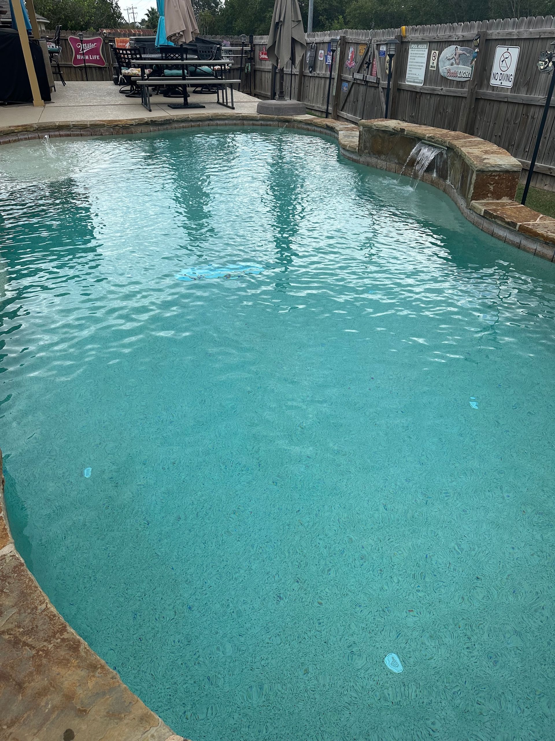 Turquoise swimming pool with stone walls and lounge chairs at the far end