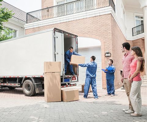Young Couple Watching Movers Move Boxes from the Moving Van — Columbus, GA — Sanera Van Service Inc.