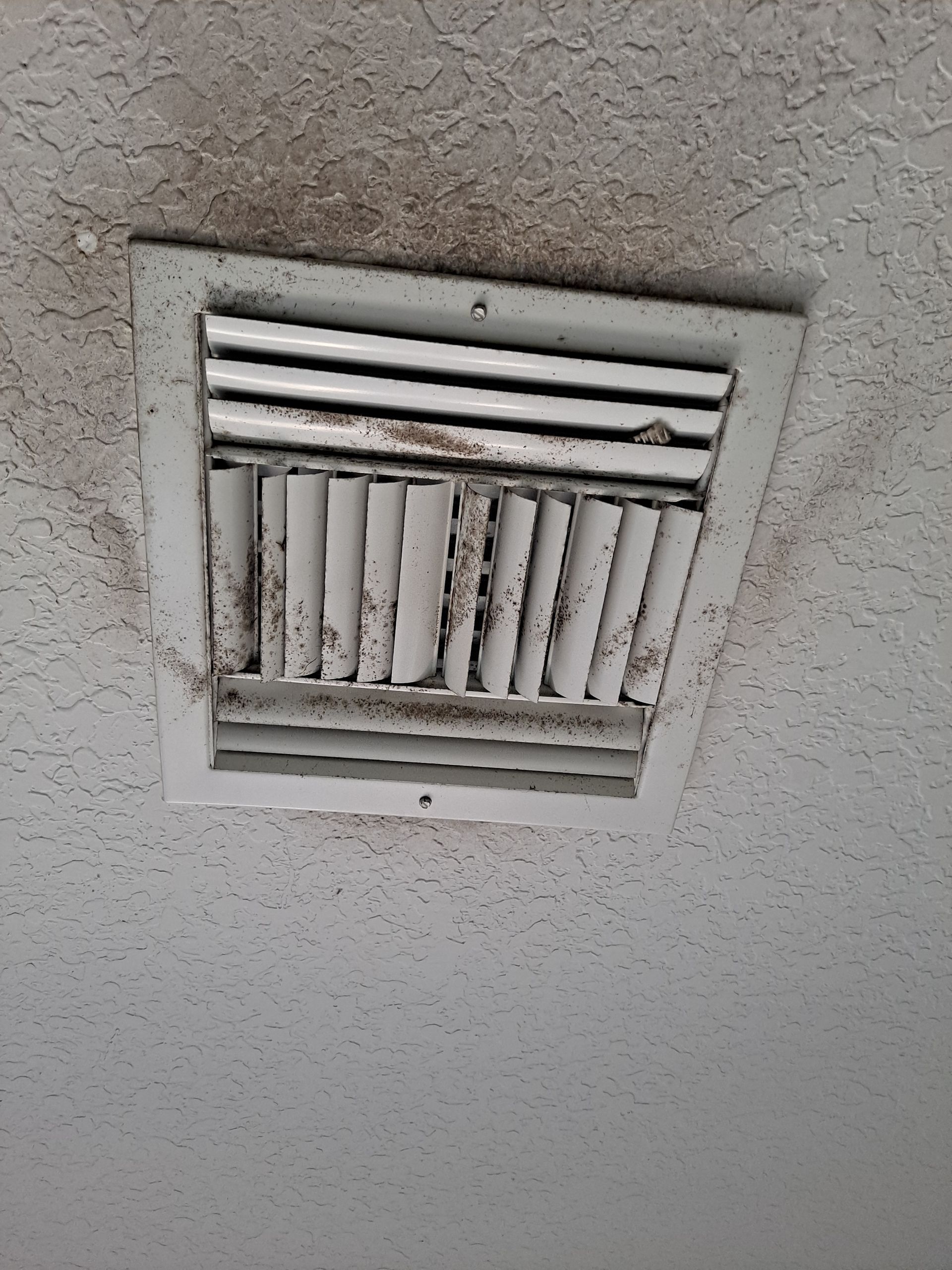 A dirty air vent on the ceiling of a building.