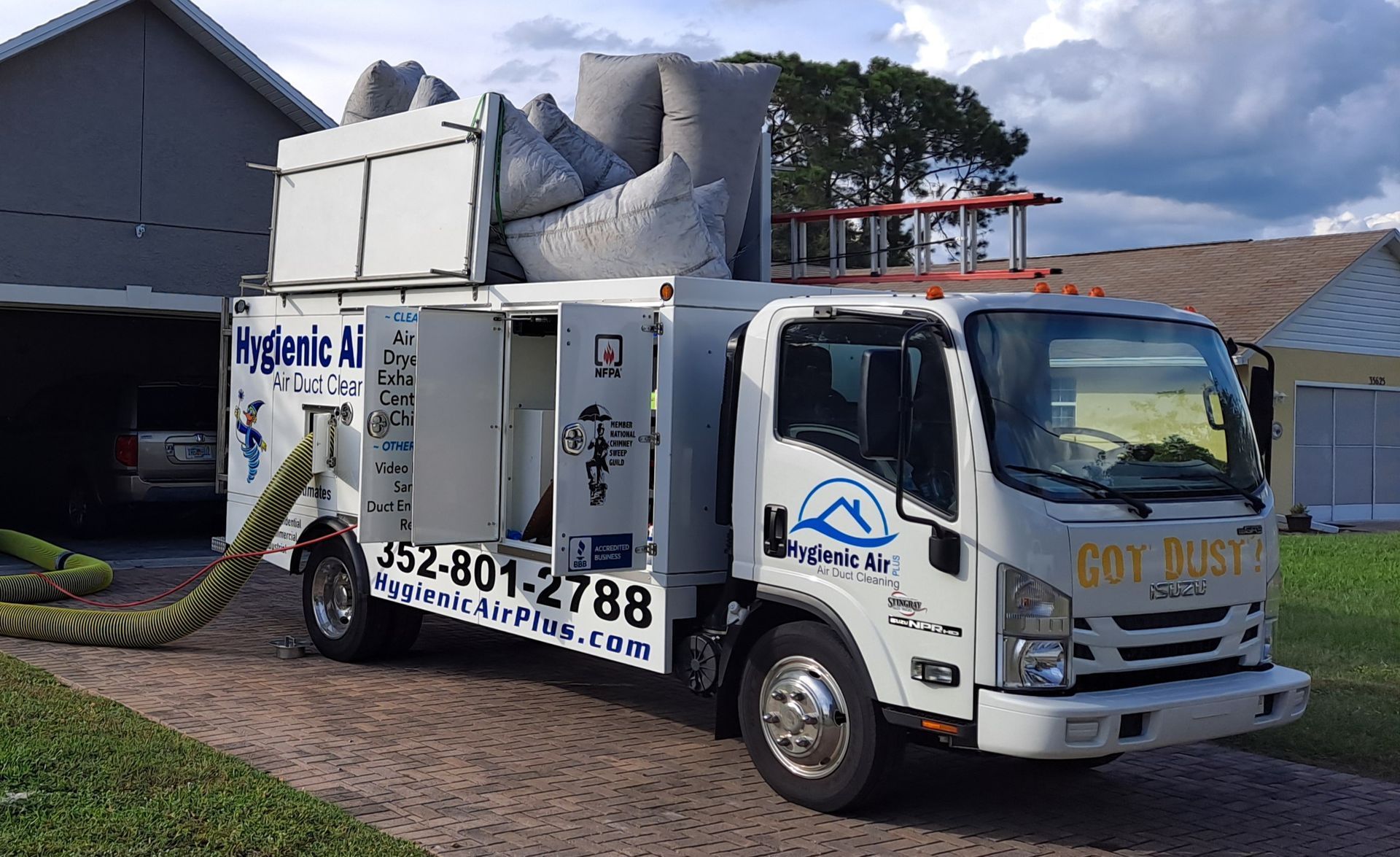 A white dry dust truck is parked in front of a house.