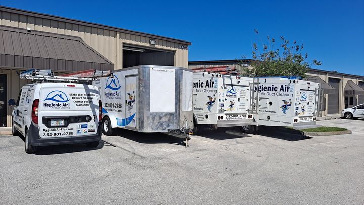 Two vans and two trailers are parked in front of a building.