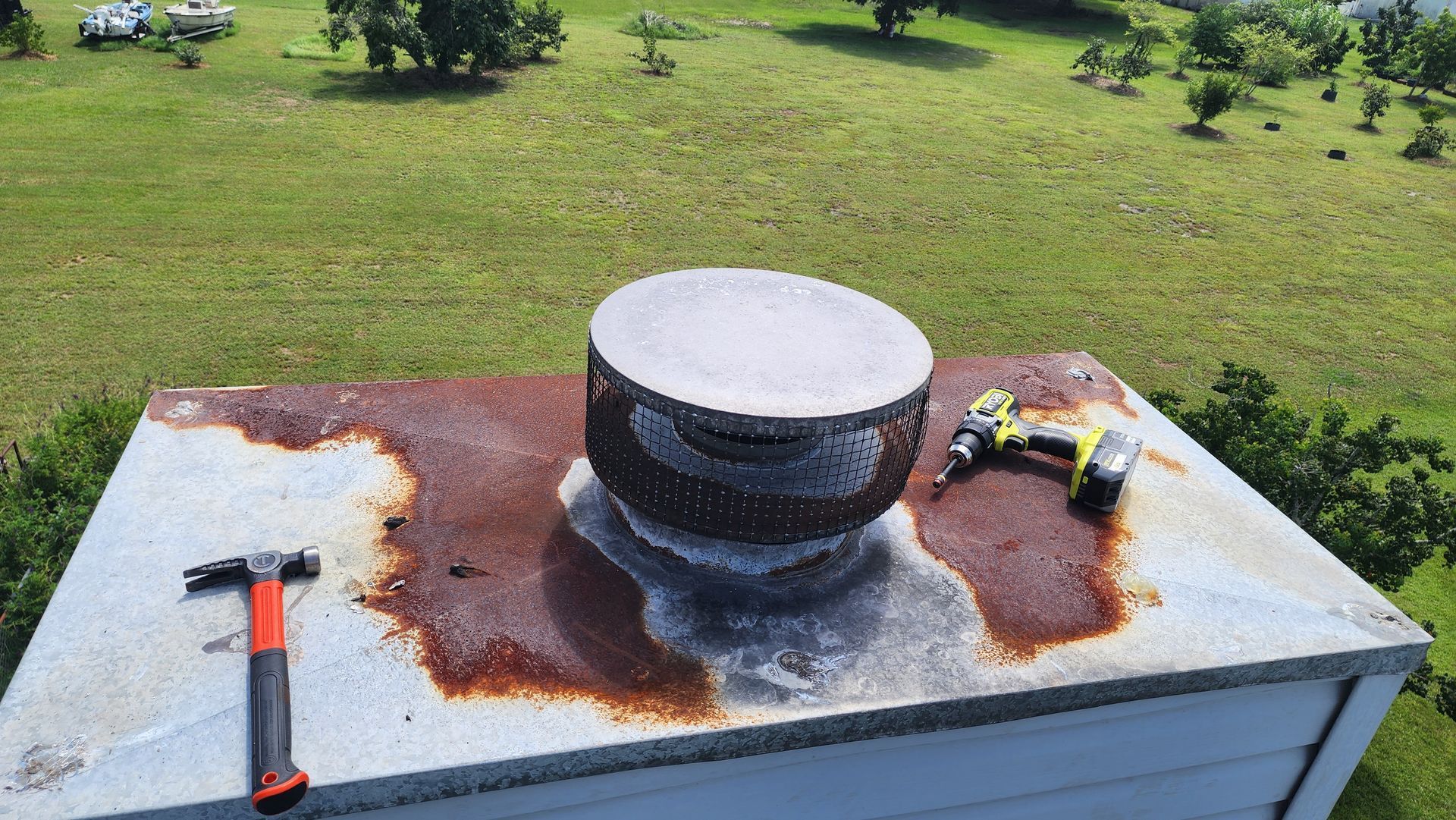 A rusty chimney with a hammer and drill on top of it.