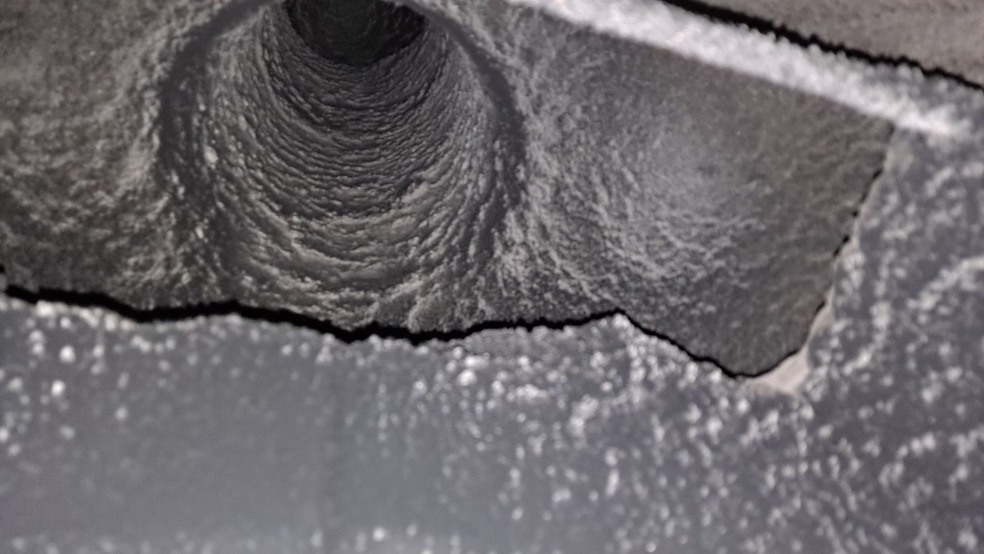 A close up of a dirty air duct with a hole in the middle.