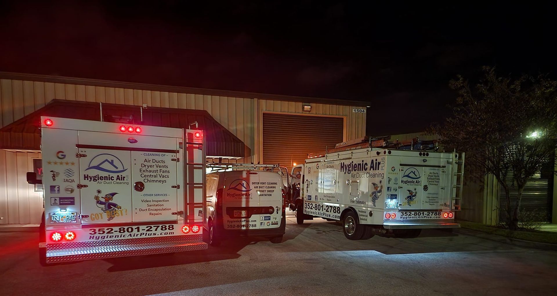 Two fire trucks are parked in front of a building at night.