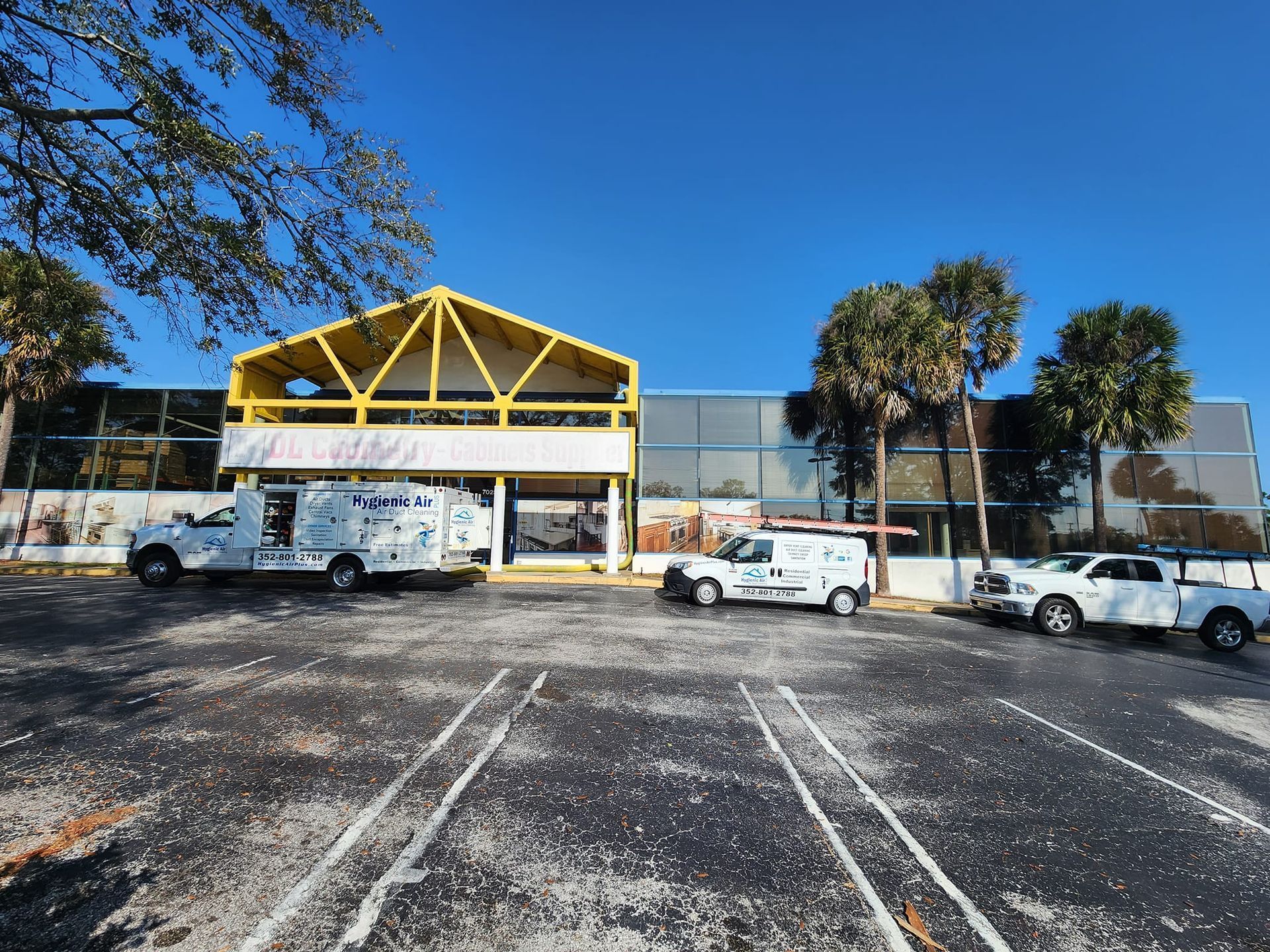 Three white vans are parked in front of a building.
