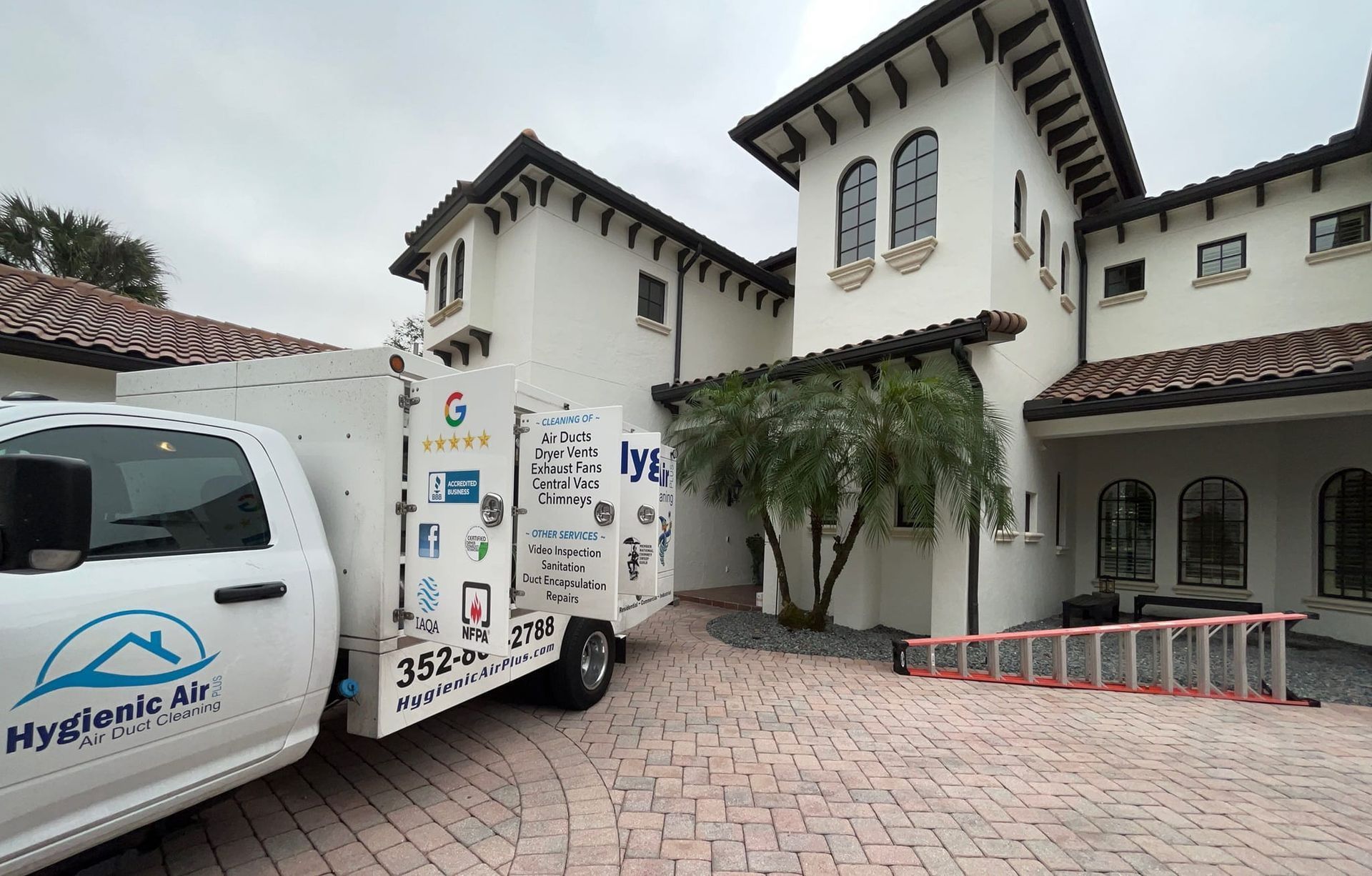 A white truck is parked in front of a large white house.