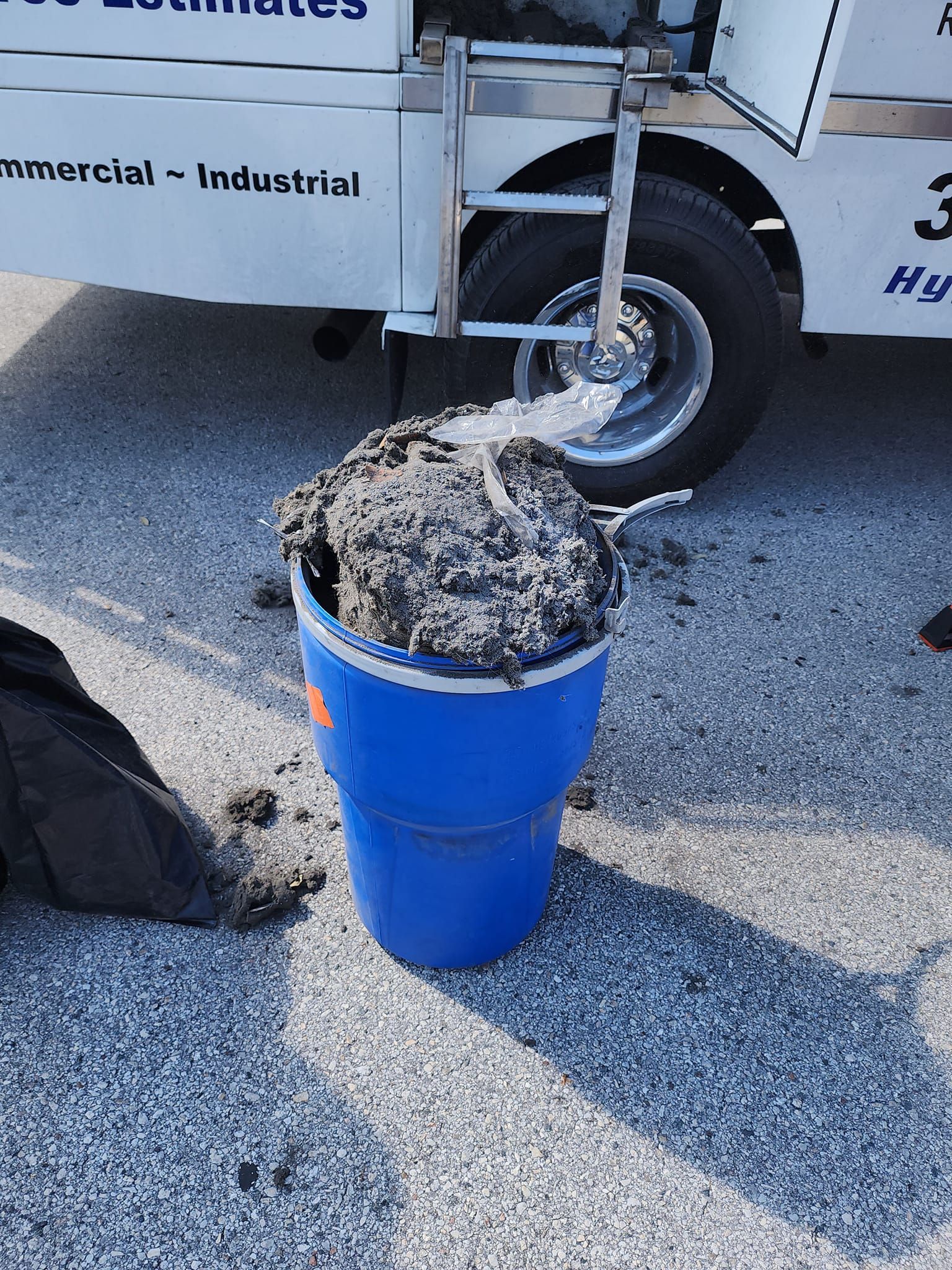 A blue bucket filled with dirt is in front of a truck that says commercial industrial