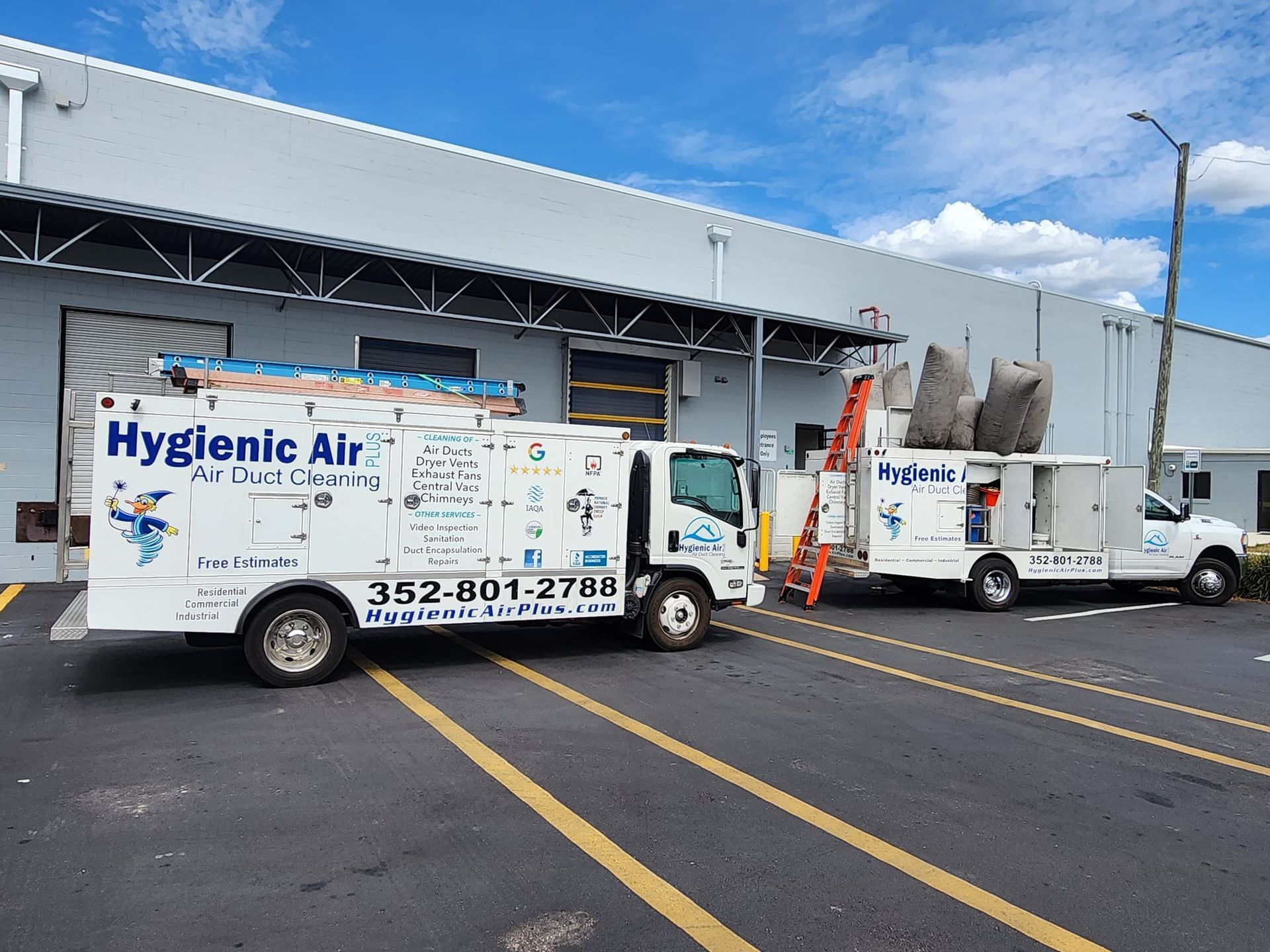 Two hygiene air trucks are parked in front of a building.