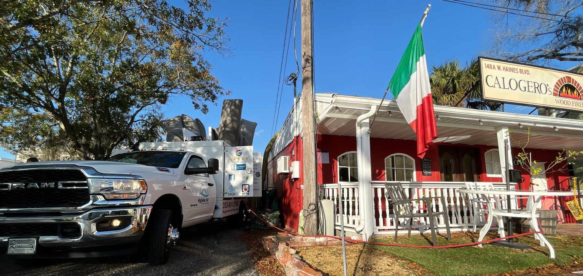 A white truck is parked in front of a restaurant.