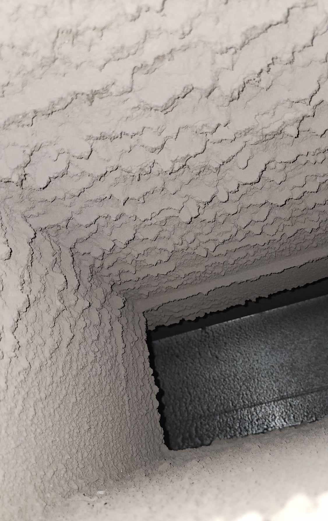 A black and white photo of a dirty air vent.