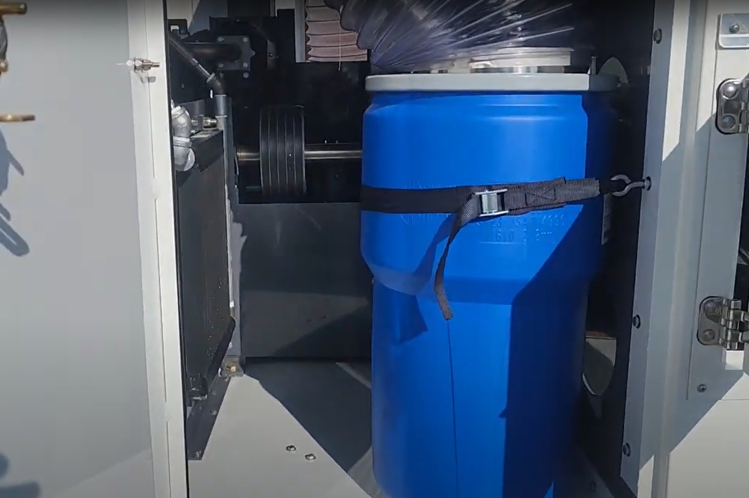 A blue plastic barrel is sitting inside of a machine.