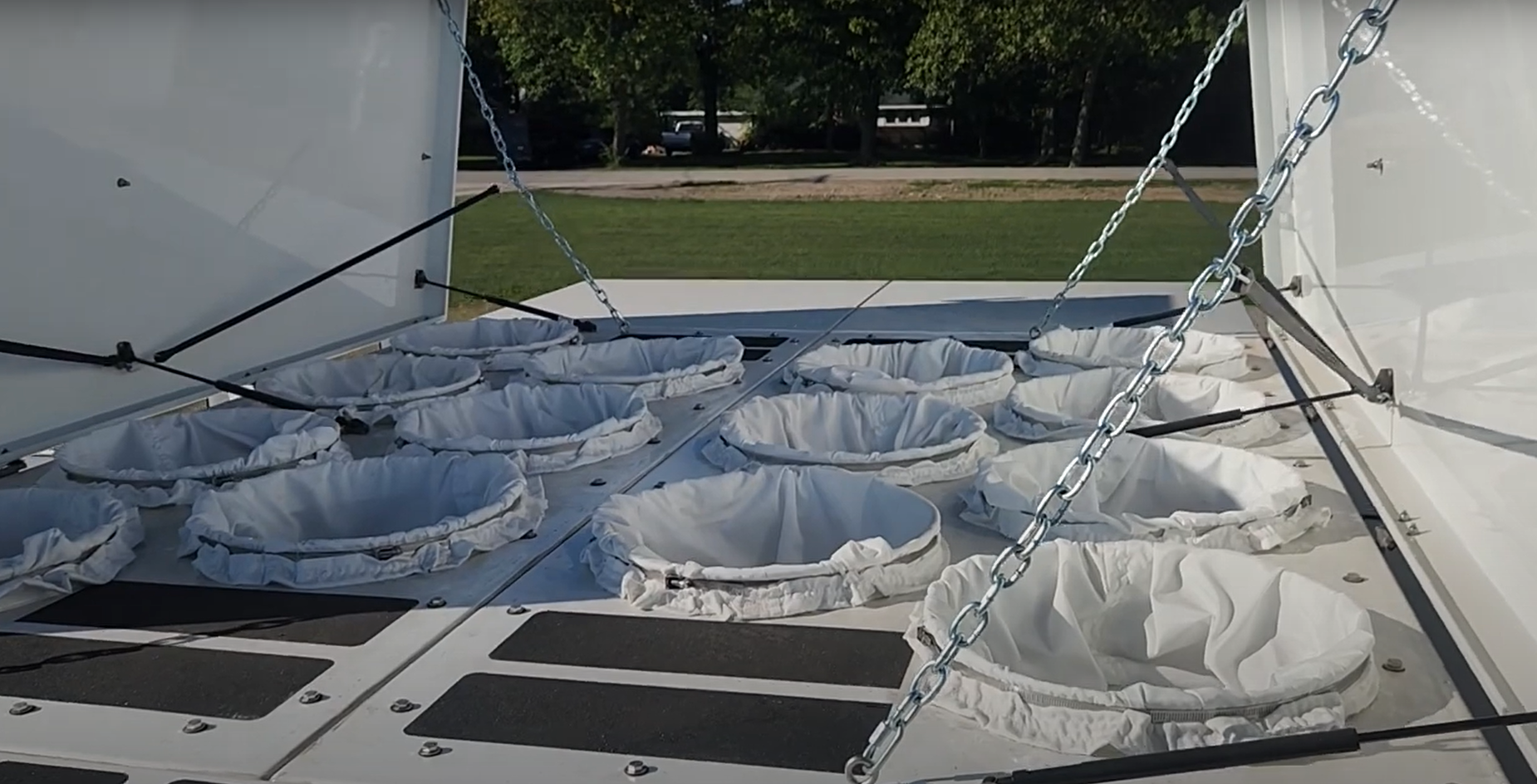 A bunch of white bags are hanging from chains on a roof.