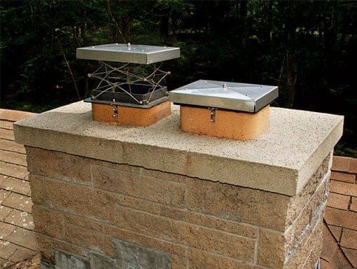 Two chimney caps are sitting on top of a brick chimney.