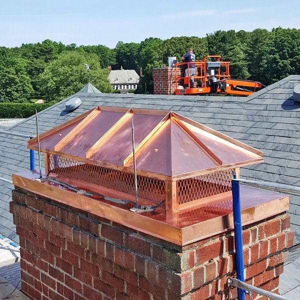 Two chimney caps are sitting on top of a brick chimney.