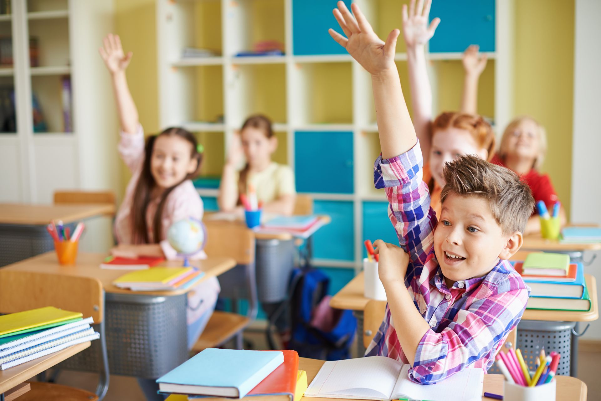 Enthusiastic children in school raising their hands, symbolizing improved focus and academic perform