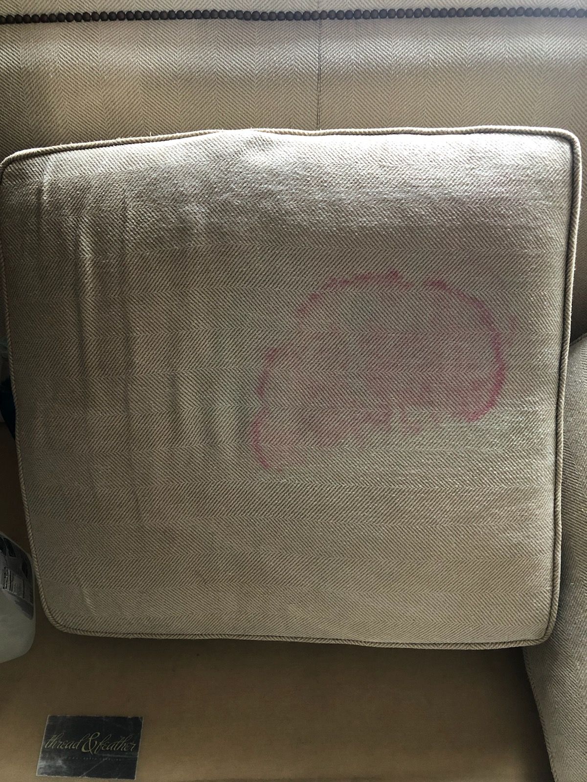 A couch with a red stain on the back of it.