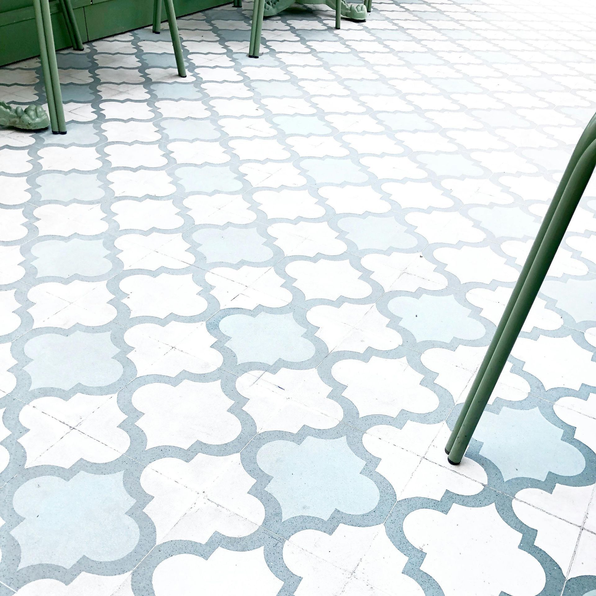 A white tile floor with a green chair in the background