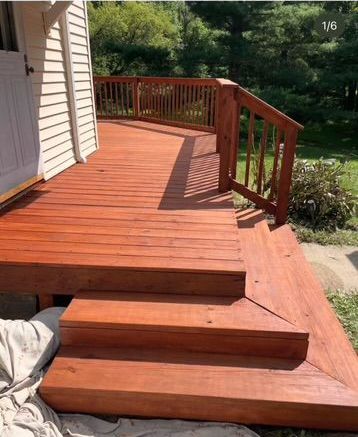 A wooden deck with stairs leading up to it next to a house.