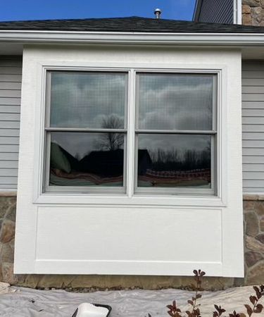 A white window on the side of a house is being painted.