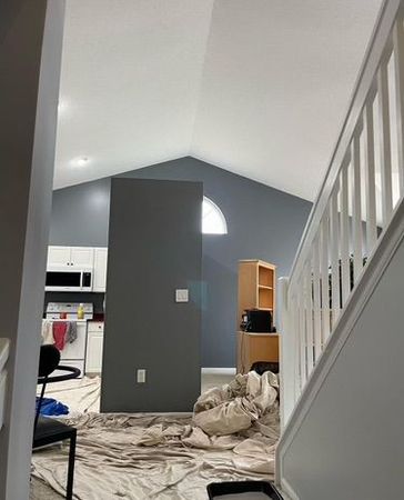 A living room with a staircase leading up to it and a kitchen in the background.