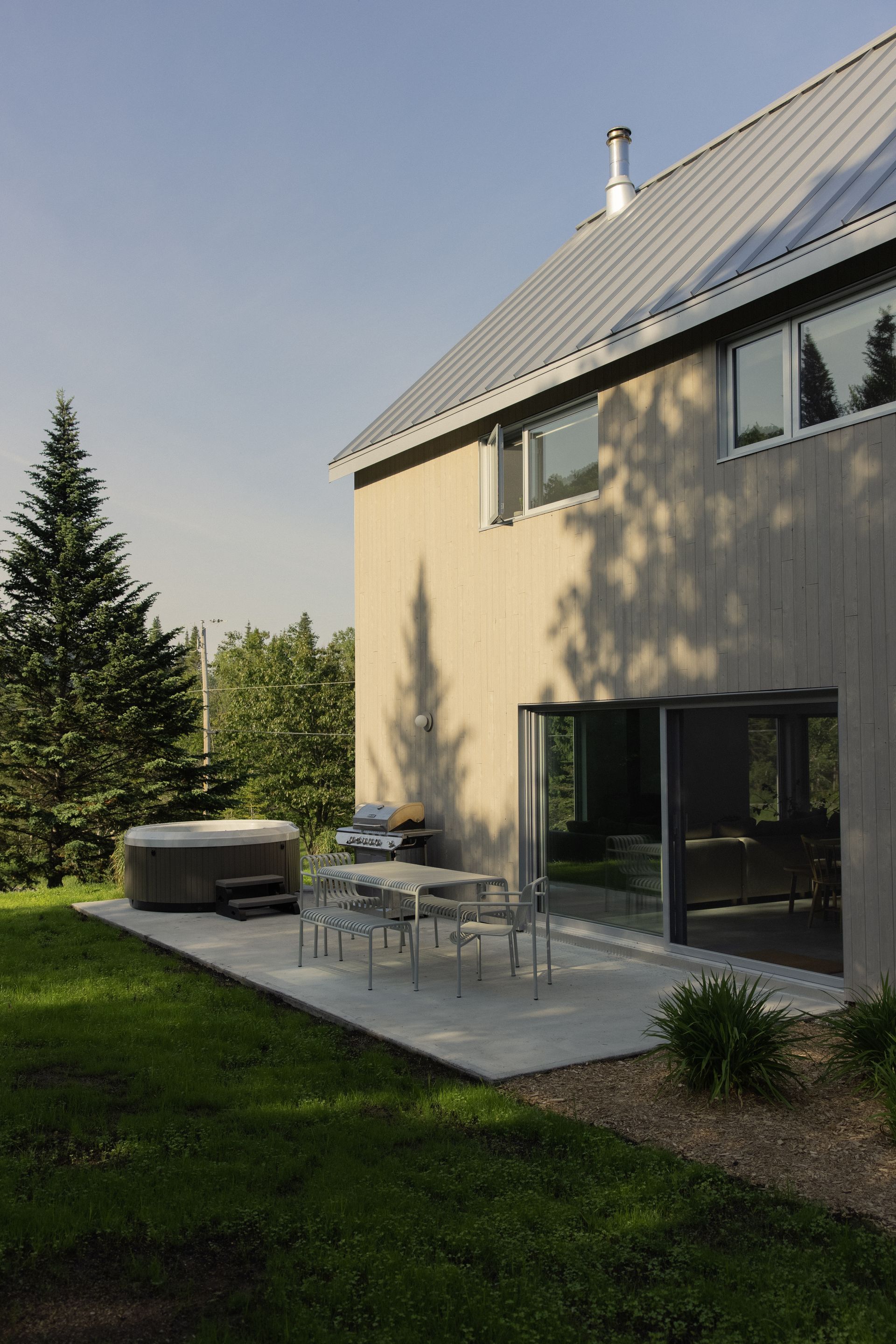 Une maison avec un patio et un bain à remous devant