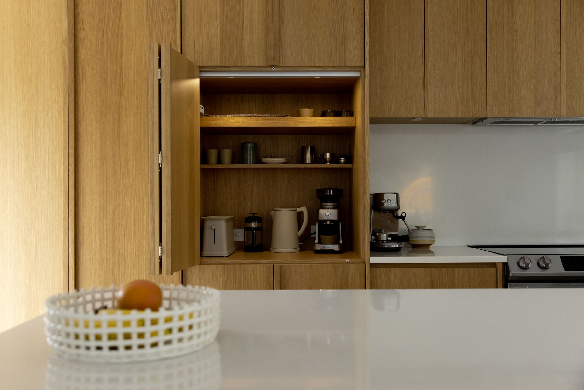 Une cuisine avec armoires en bois et une corbeille de fruits sur le comptoir.