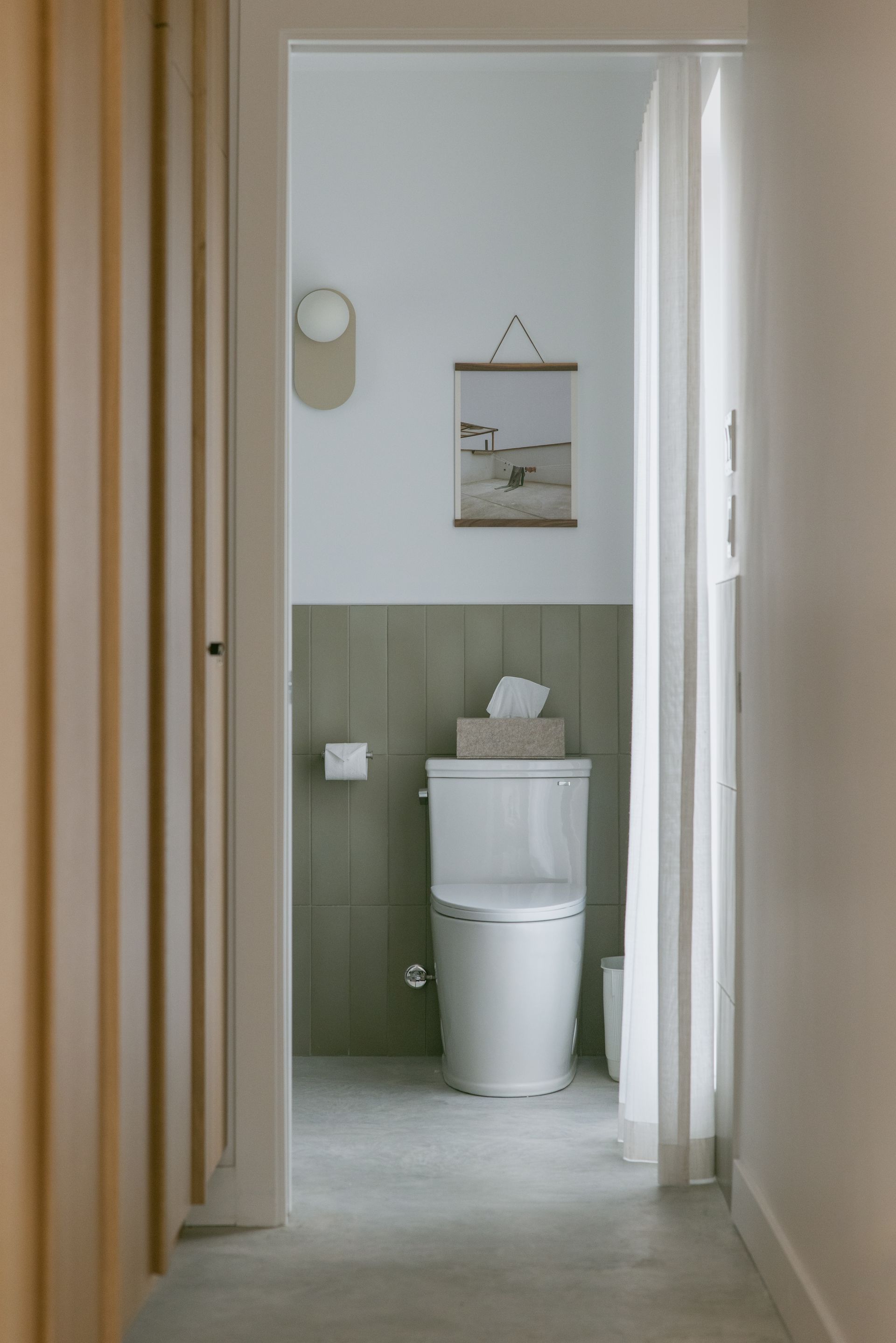 Une salle de bain avec toilettes, mouchoirs et un tableau au mur.