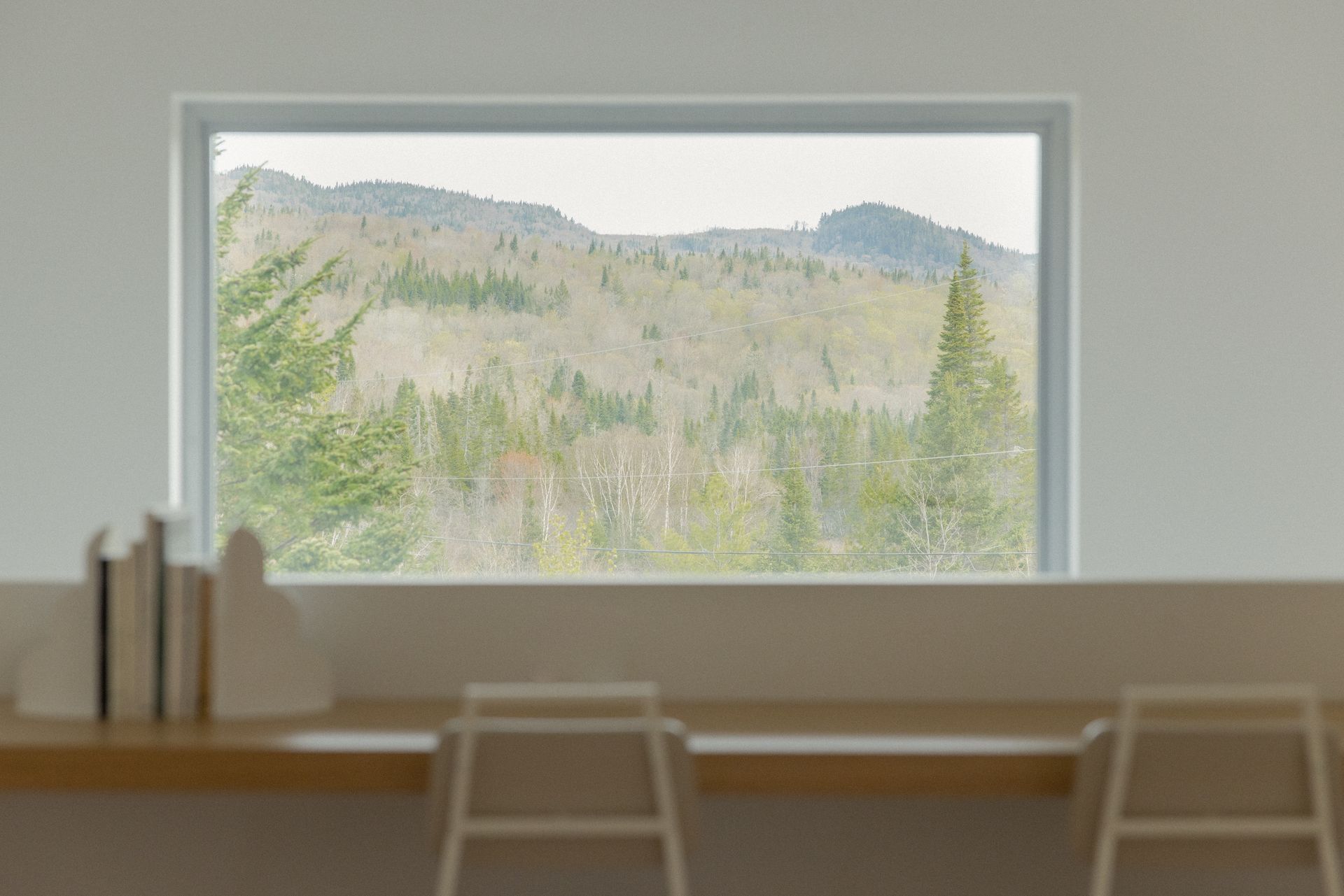 Une fenêtre dans une pièce avec vue sur une forêt et des montagnes.