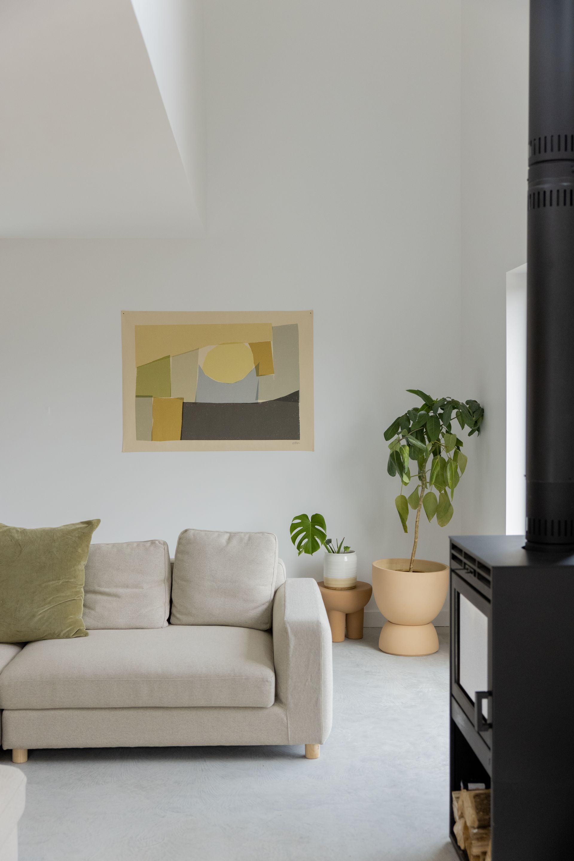 Un salon avec un canapé, une cheminée, une plante en pot et une peinture au mur.