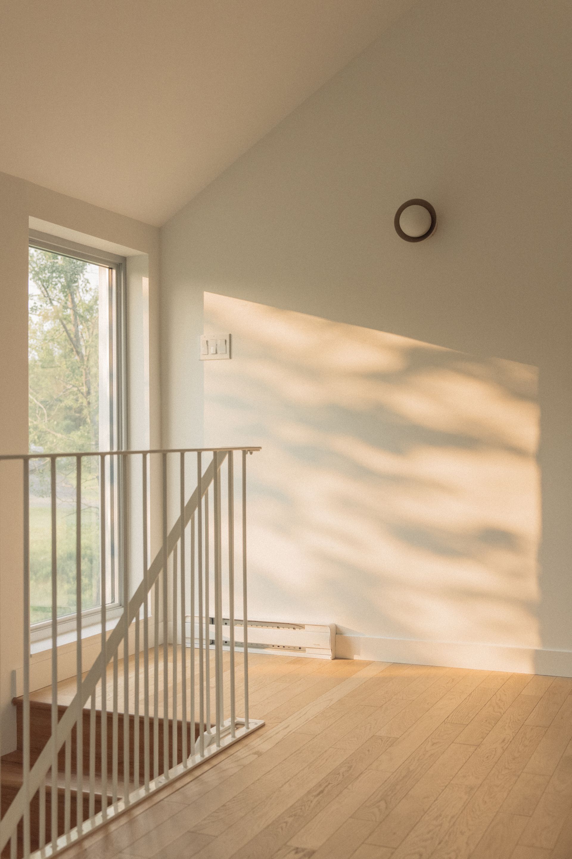 Une pièce avec un escalier et une fenêtre avec le soleil qui brille à travers elle.