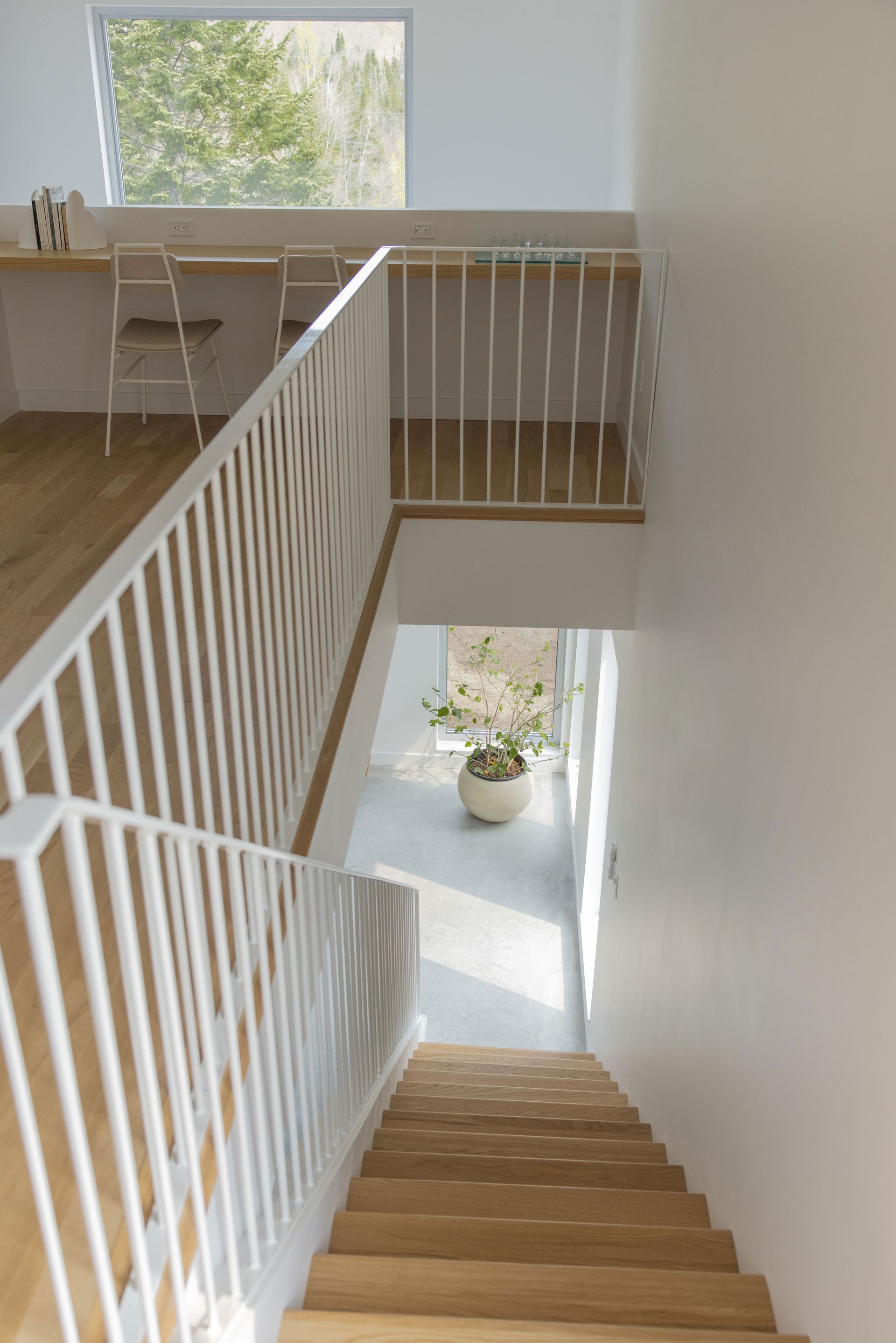 Un escalier en bois avec une rampe blanche menant au deuxième étage d'une maison.