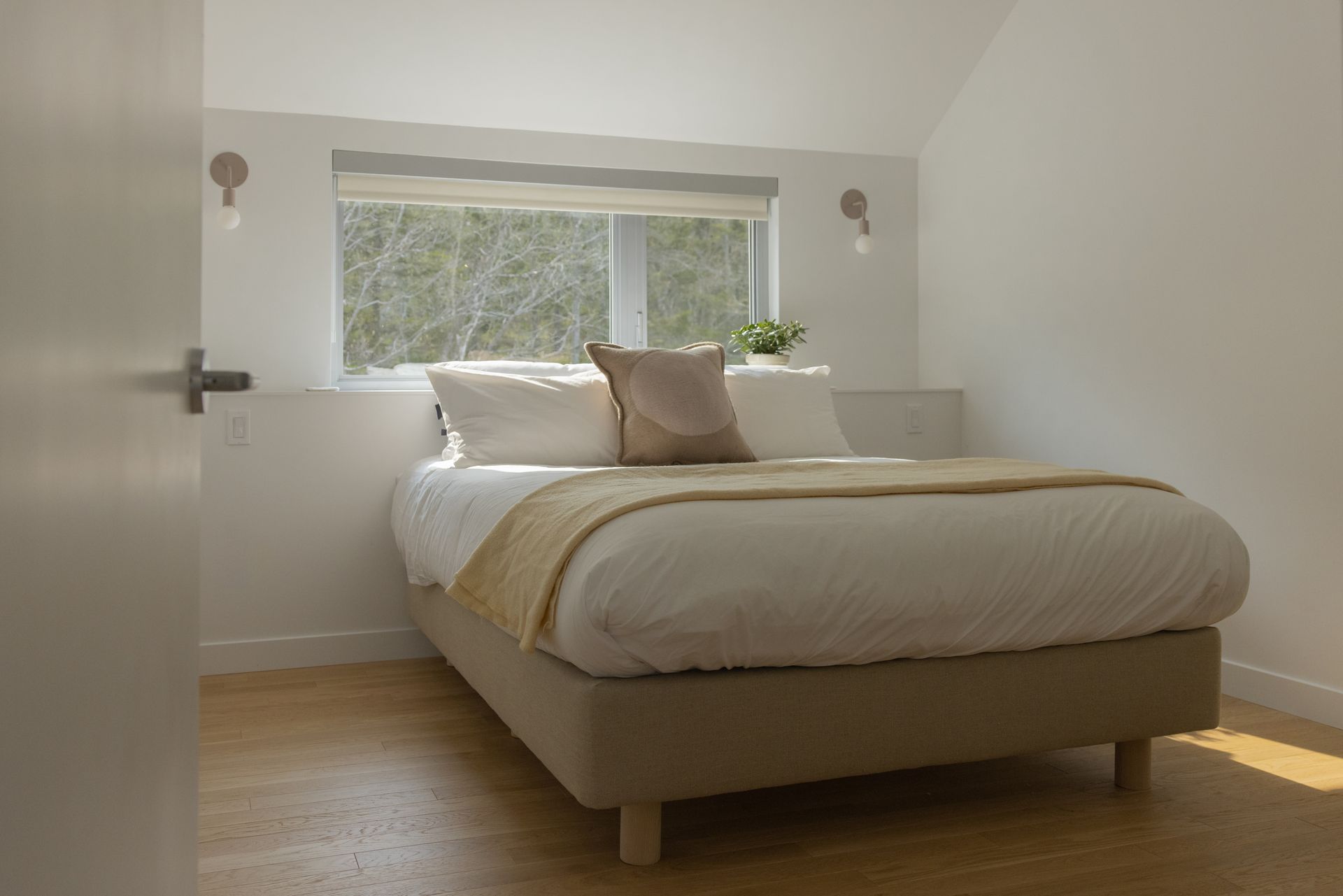 Une chambre avec un lit , fenêtre et parquet.