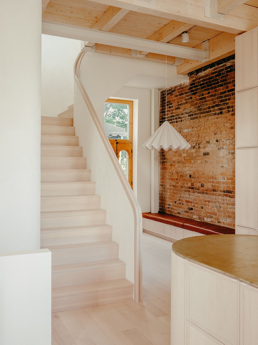 Une cuisine avec un escalier menant au deuxième étage et un mur de briques.