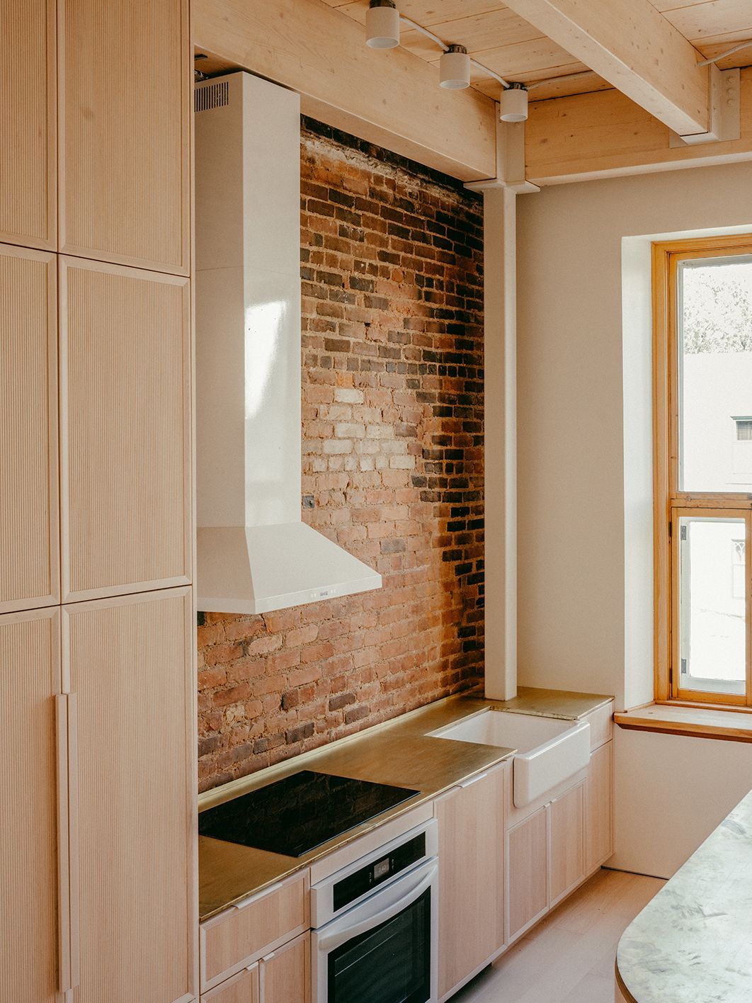 Une cuisine avec un mur de briques, des armoires en bois, une cuisinière et un évier.
