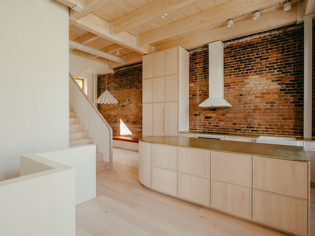 Une cuisine avec armoires en bois et mur de brique.