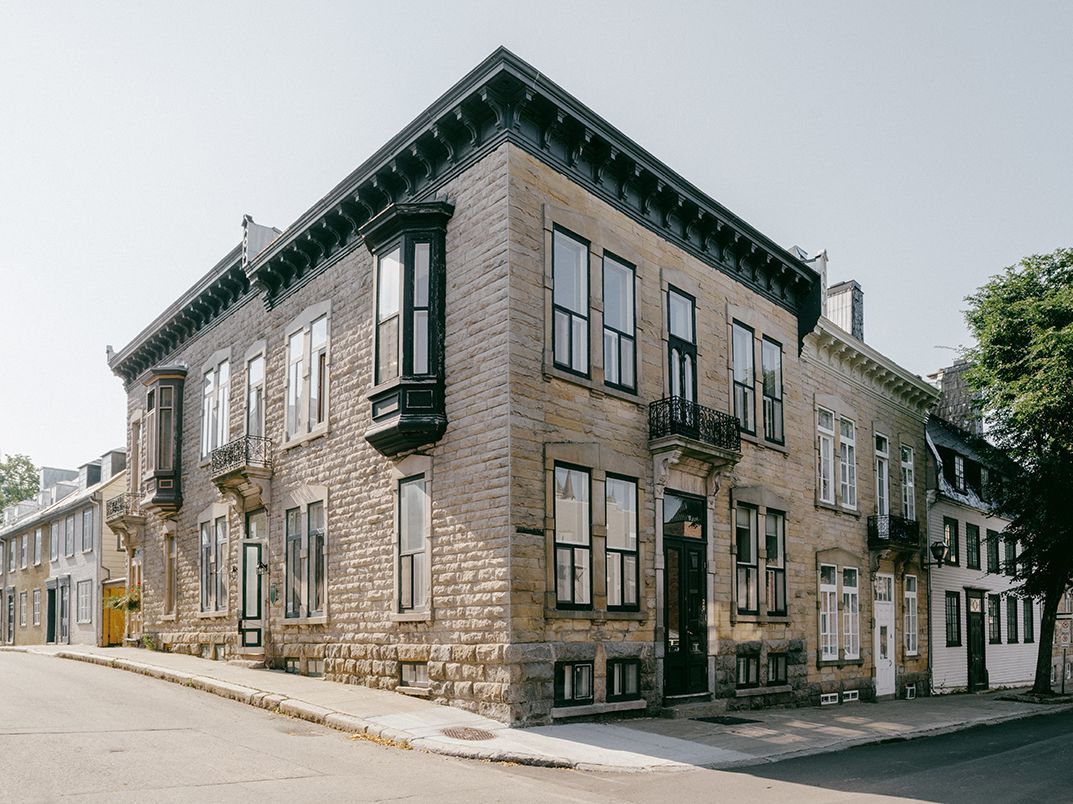 Un grand bâtiment en brique avec de nombreuses fenêtres se trouve au coin d'une rue.