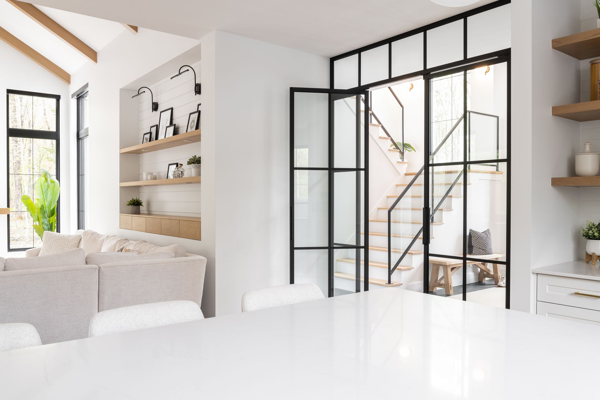 Un séjour avec un escalier et une porte vitrée coulissante.