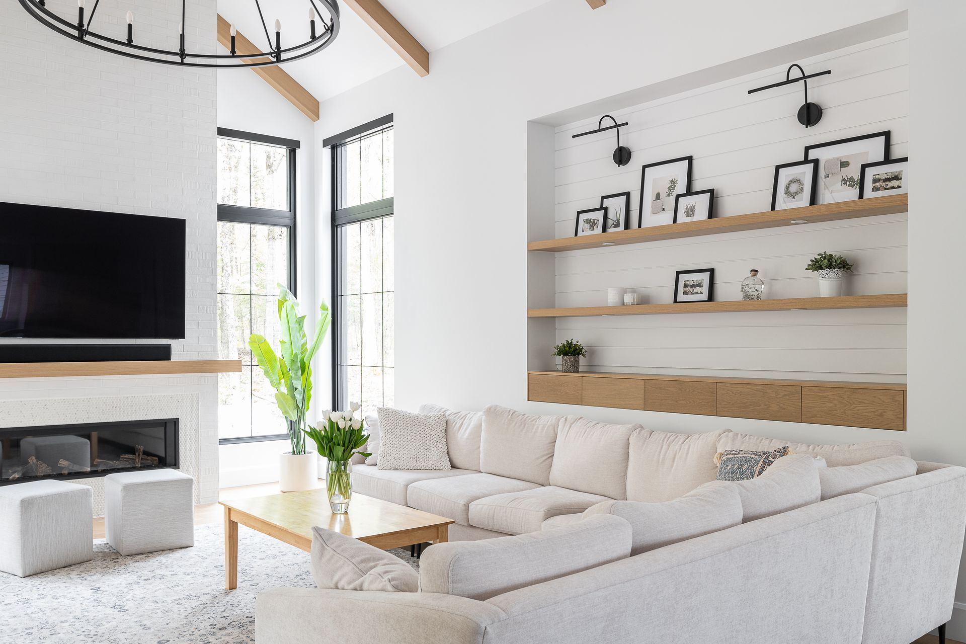 Un salon avec des meubles blancs, une cheminée et une télévision à écran plat.