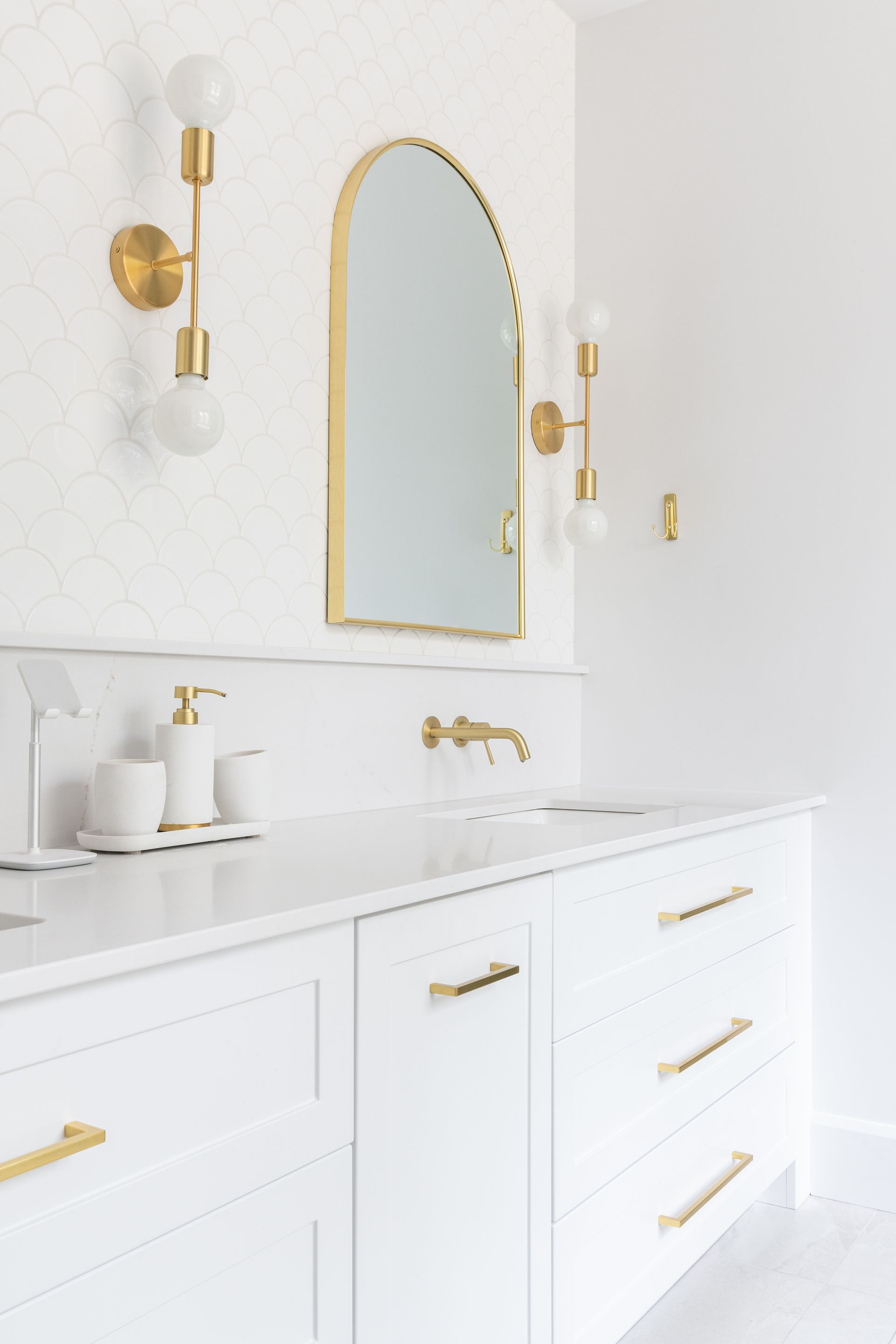 Une salle de bain avec des armoires blanches, un lavabo et un miroir.