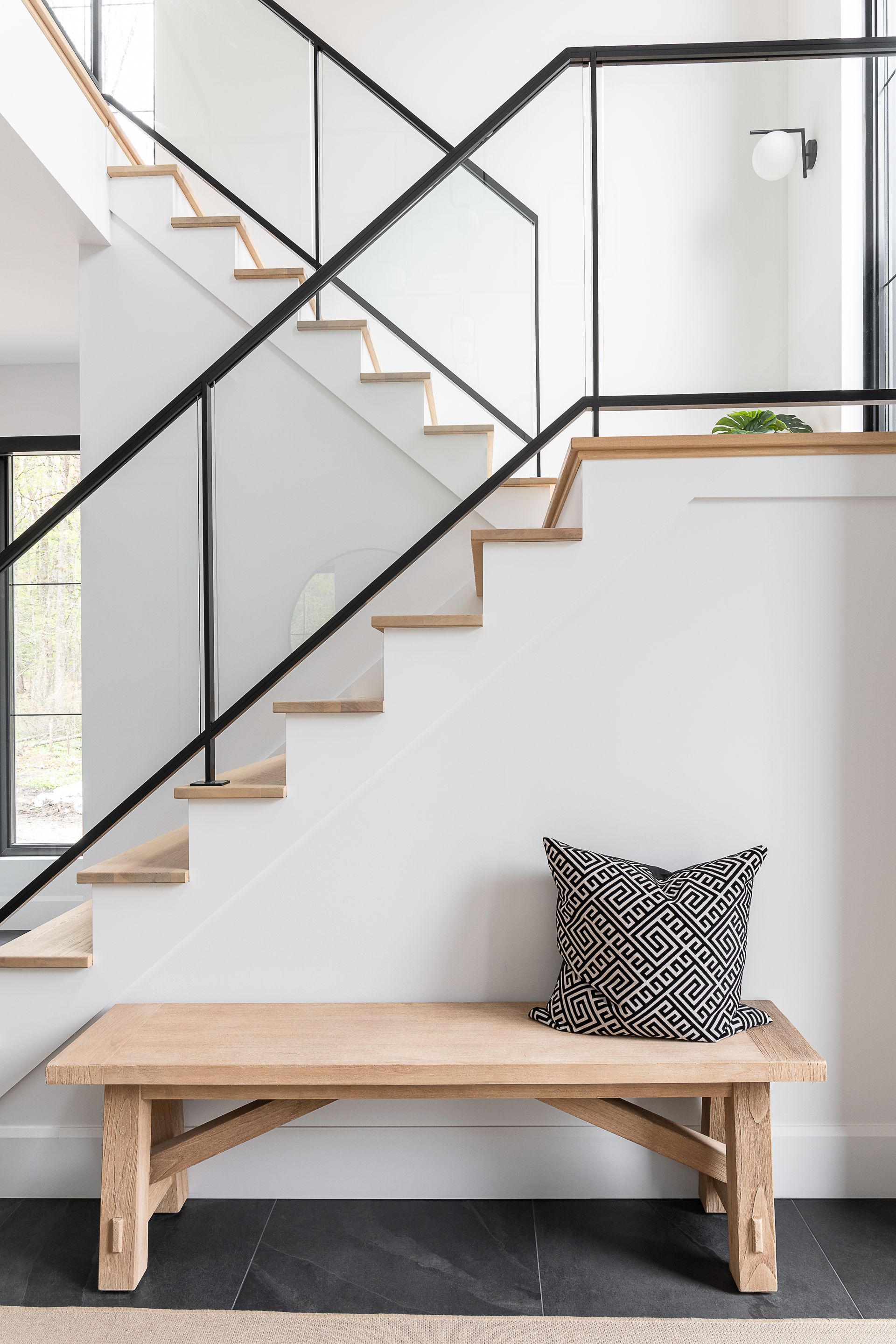 Un banc en bois avec un oreiller dessus devant un escalier.
