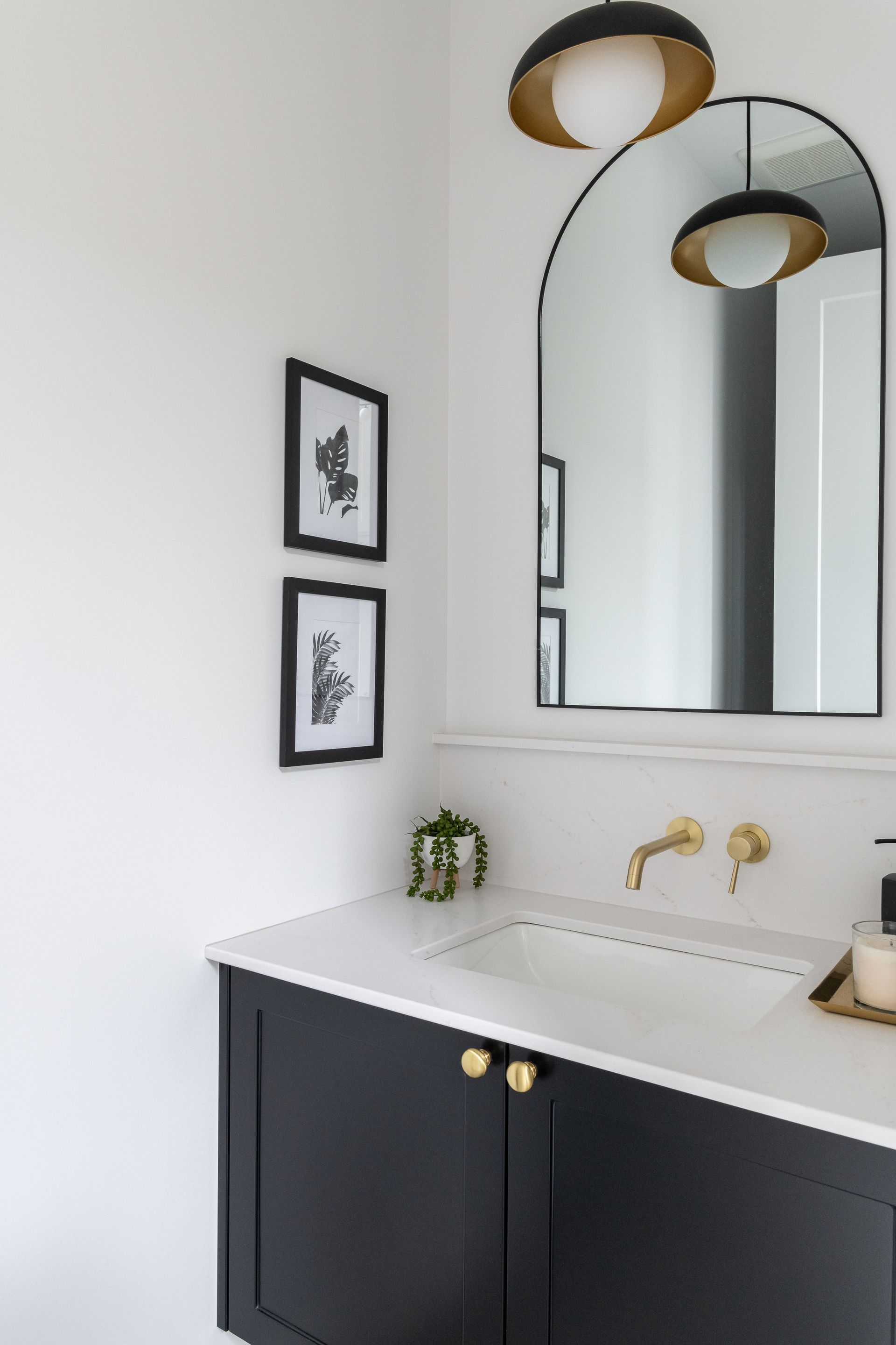 Une salle de bain avec lavabo , miroir et deux tableaux au mur.