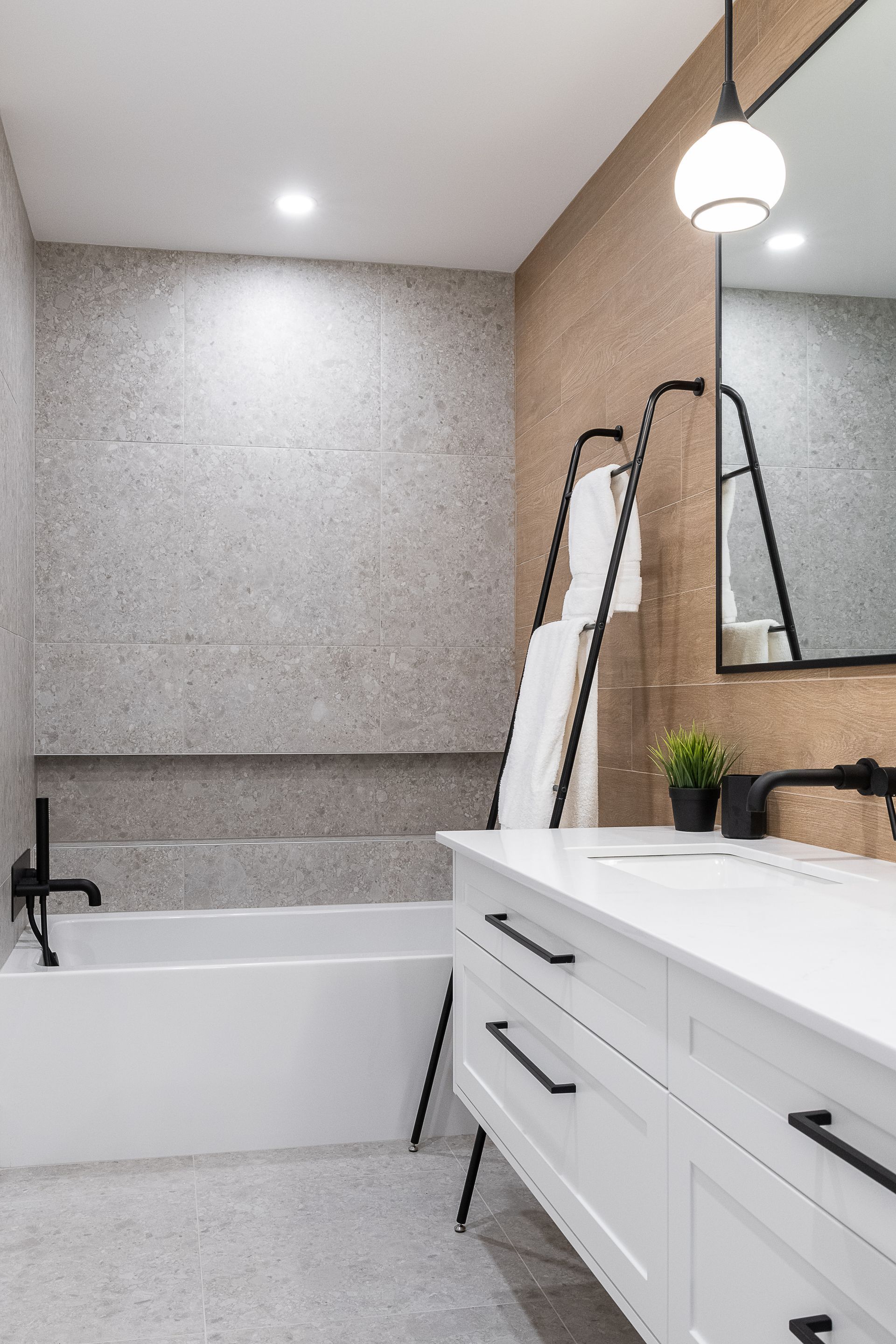 Une salle de bain avec baignoire, lavabo, miroir et porte-serviettes.