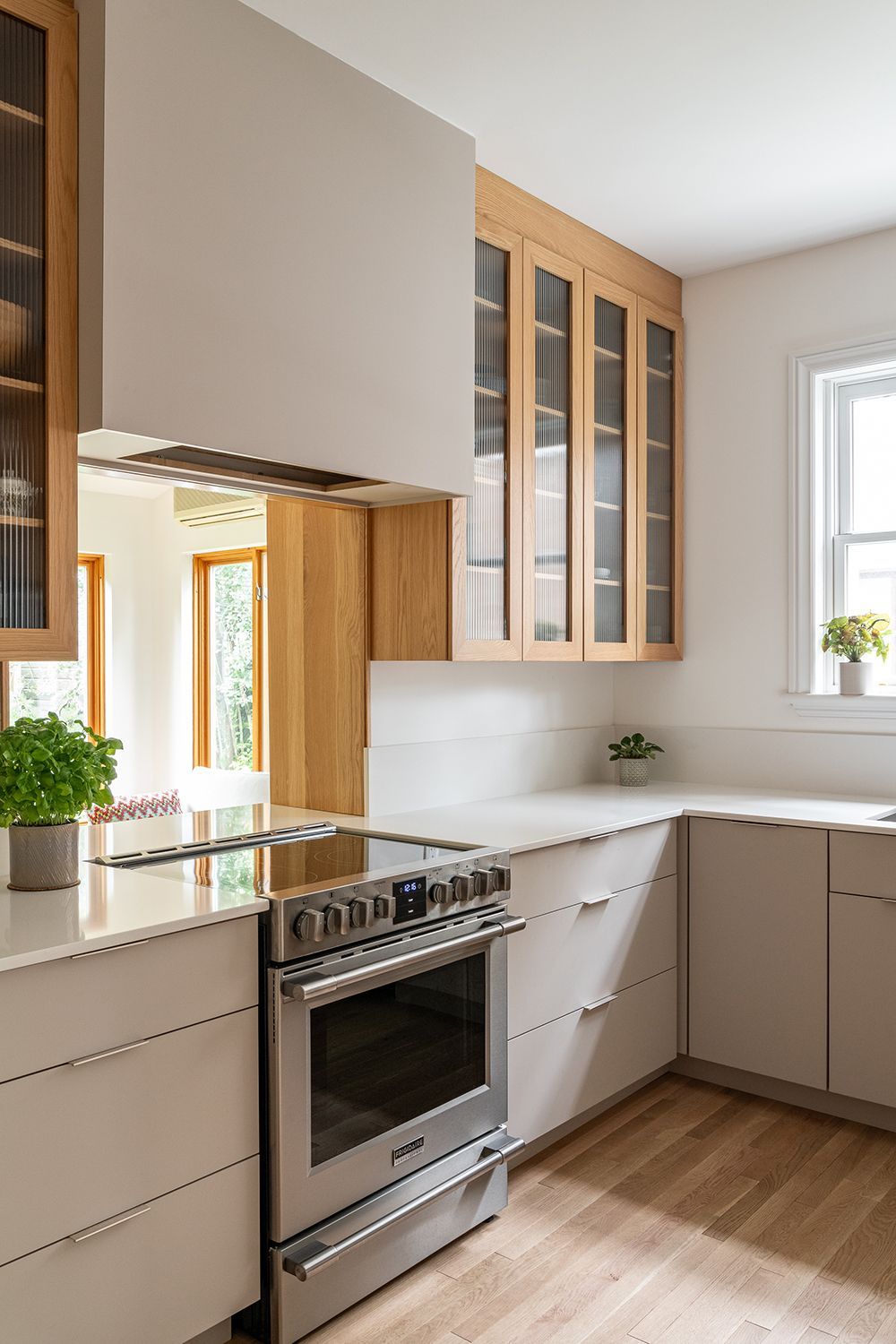 Une cuisine avec des armoires blanches, une cuisinière et une fenêtre.