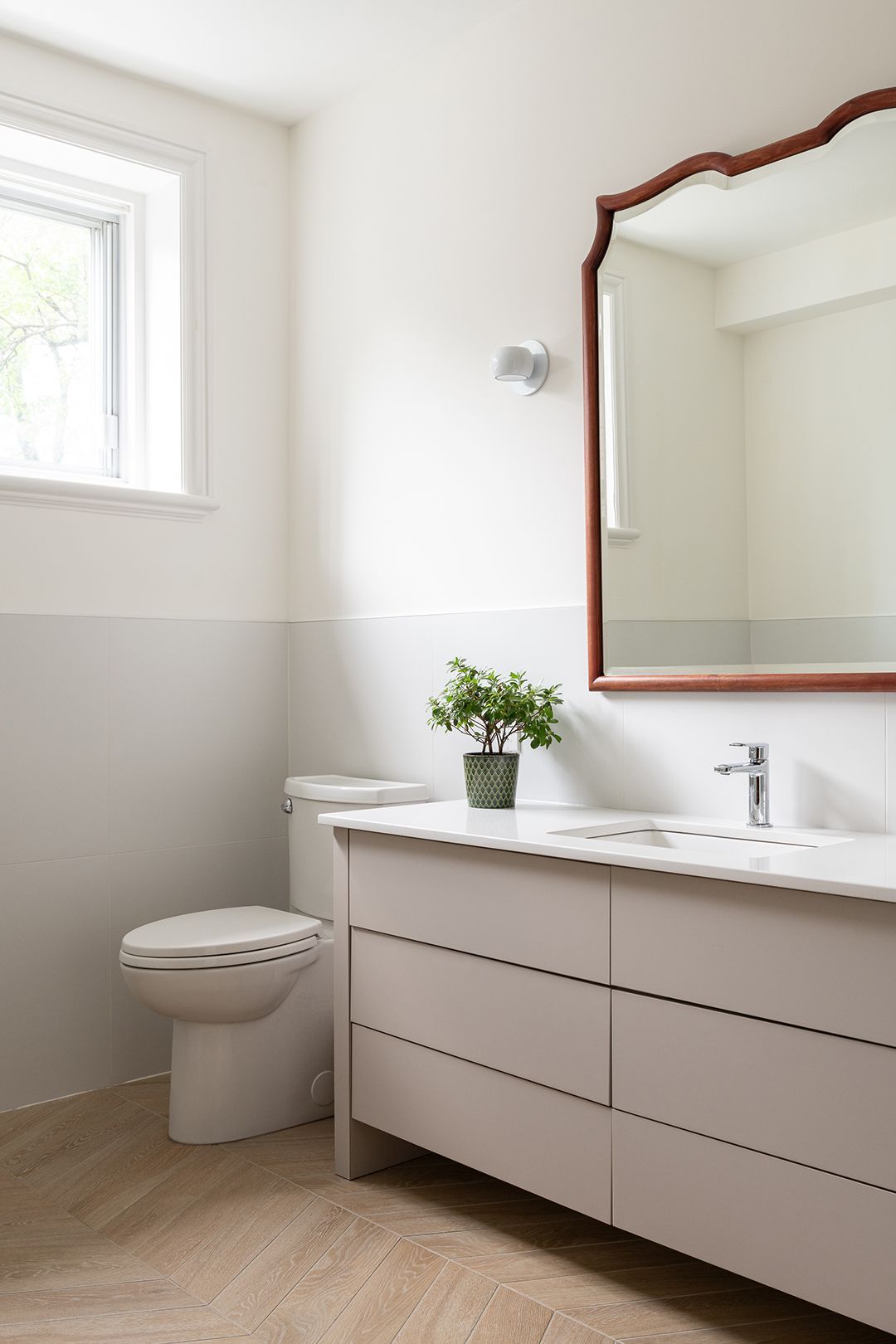 Une salle de bain avec WC , lavabo , miroir et fenêtre.