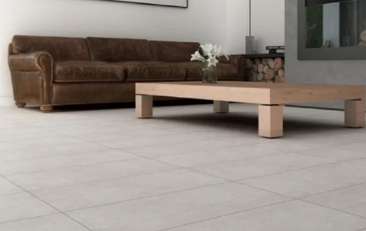 Sala de estar con sofá de cuero marrón, mesa de centro de madera y piso de baldosas de color claro.