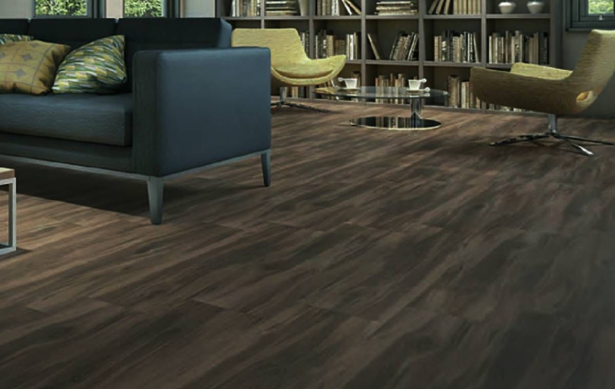 Sala de estar con piso de madera oscura, sofá negro con almohadas, sillas amarillas y estanterías.