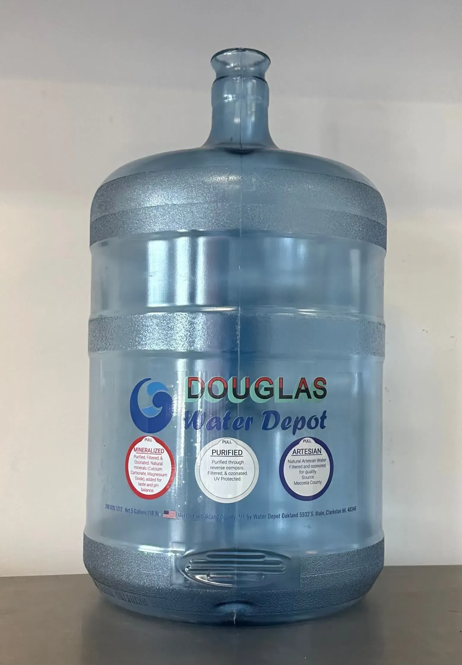 Blue plastic 5-gallon water jug from Douglas Water Depot, sitting on a surface.