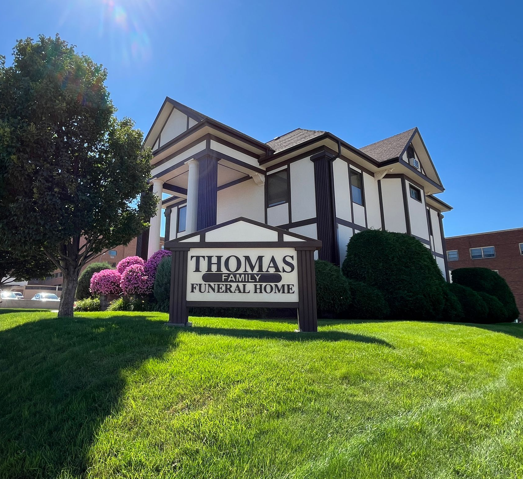 The front door of a house with a porch and plants in front of it.